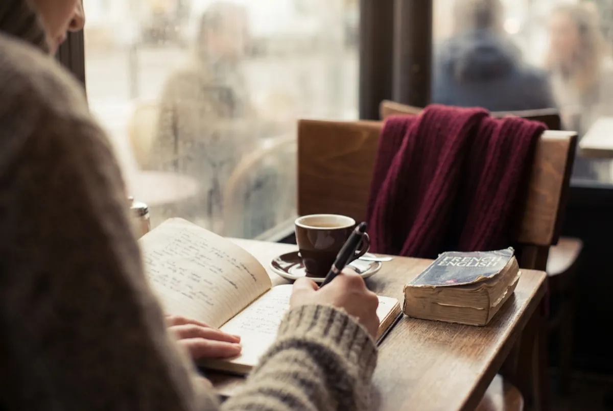Notebook, pen and a worn French pocket dictionary on a café table